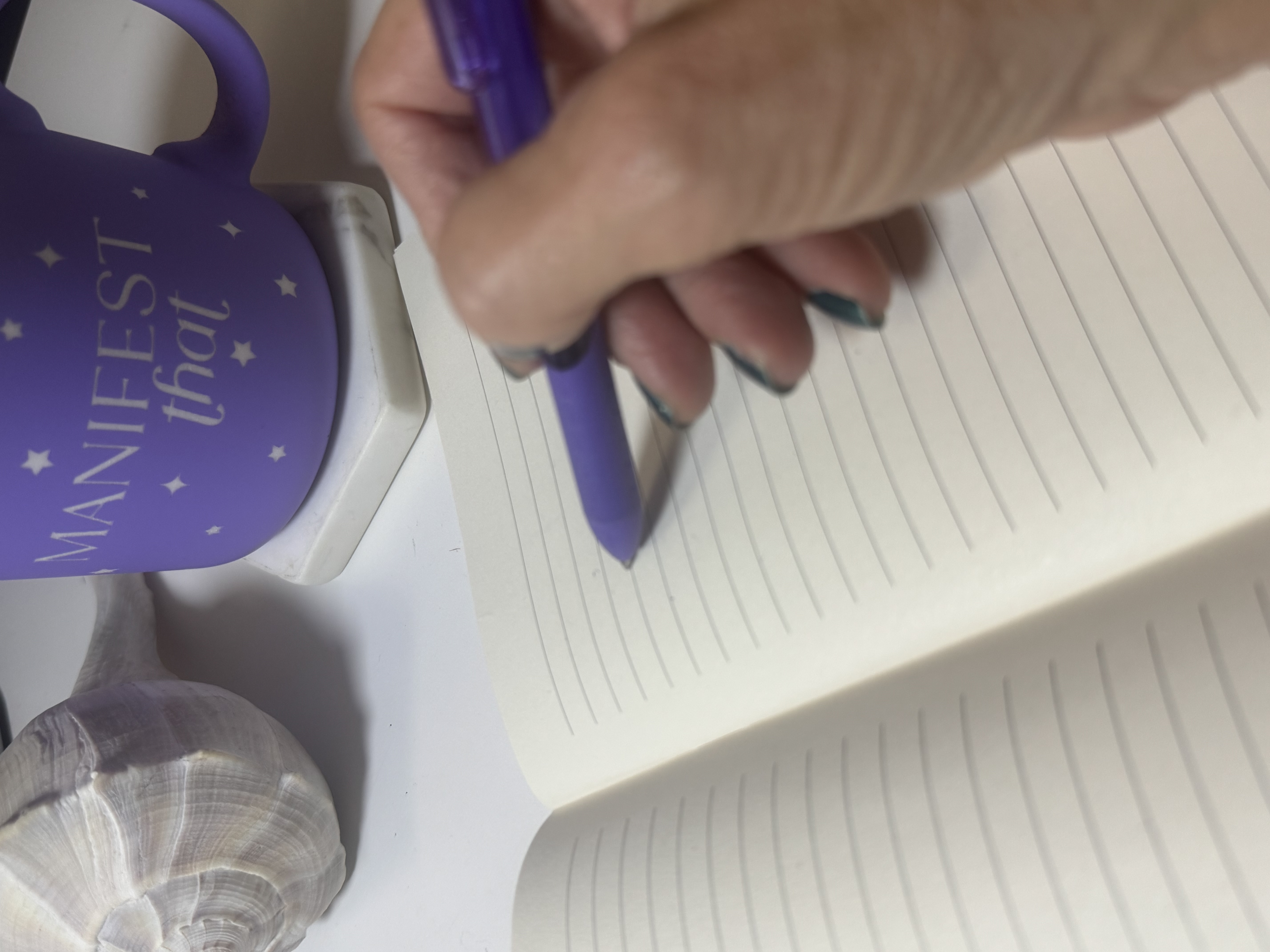 manifest mug with hand holding pen over a blank journal page for georgiaruth.com